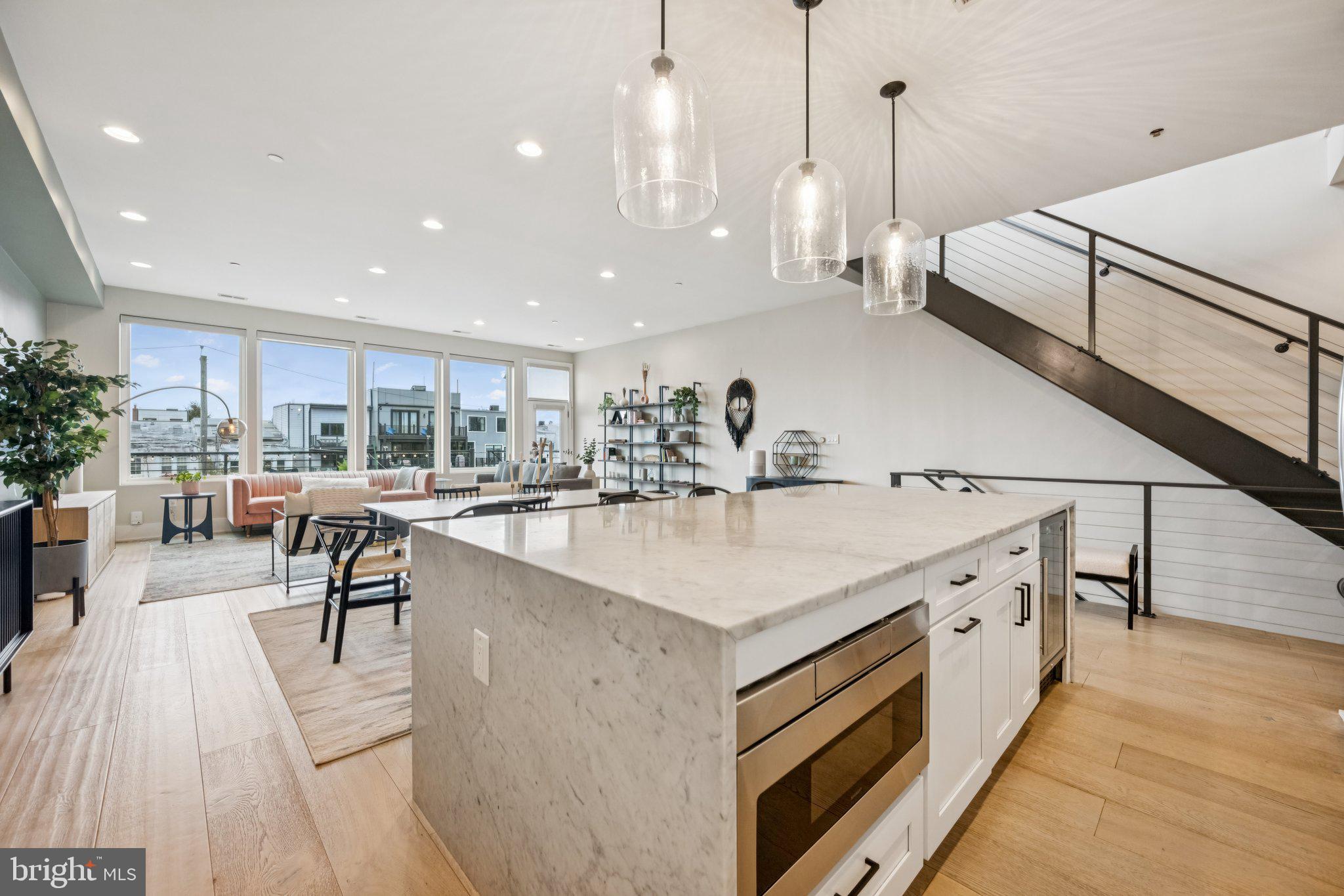 1316 Shepherd Street Northwest, Unit 4 Washington, DC 20011 - Photo 6 of 25 a large kitchen with stainless steel appliances kitchen island a large counter top a stove a chimney a sink and a living room view