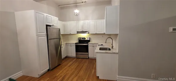 a kitchen with a refrigerator a stove top oven and wooden floor