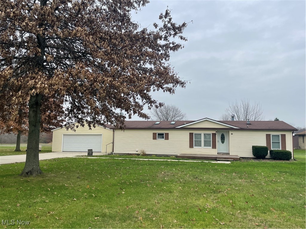 Single story home with a garage and a front lawn