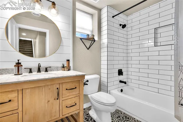 a bathroom with a granite countertop toilet a sink a mirror a bathtub and shower