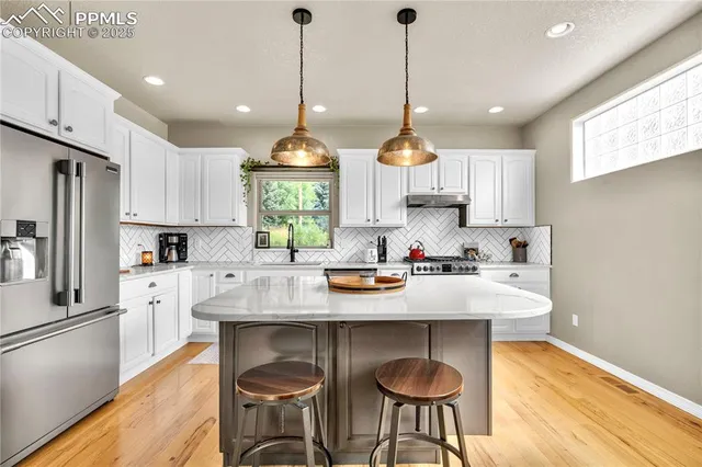 a kitchen with stainless steel appliances granite countertop a sink a stove a refrigerator cabinets and chairs