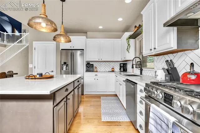a kitchen with stainless steel appliances a sink a stove top oven a counter space and cabinets