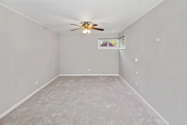 an empty room with windows and chandelier fan
