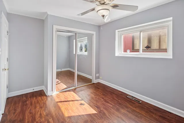 a view of empty room with wooden floor and fan