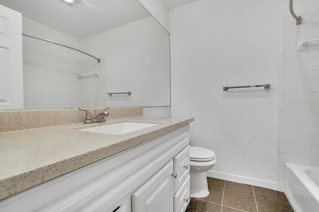 a bathroom with a granite countertop sink a toilet and a mirror