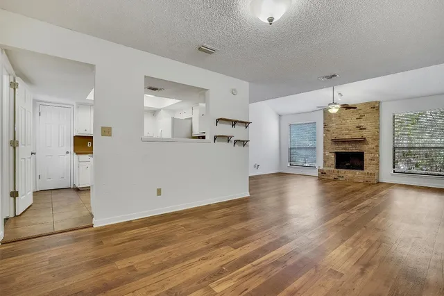 an empty room with wooden floor and a kitchen