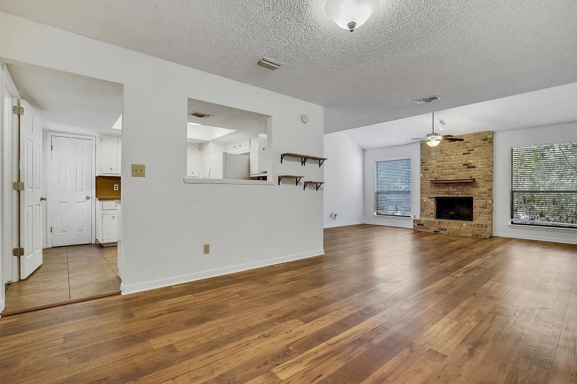 3201 Twinberry Cove, Unit B Austin, TX 78746 - Photo 5 of 19 an empty room with wooden floor and a kitchen