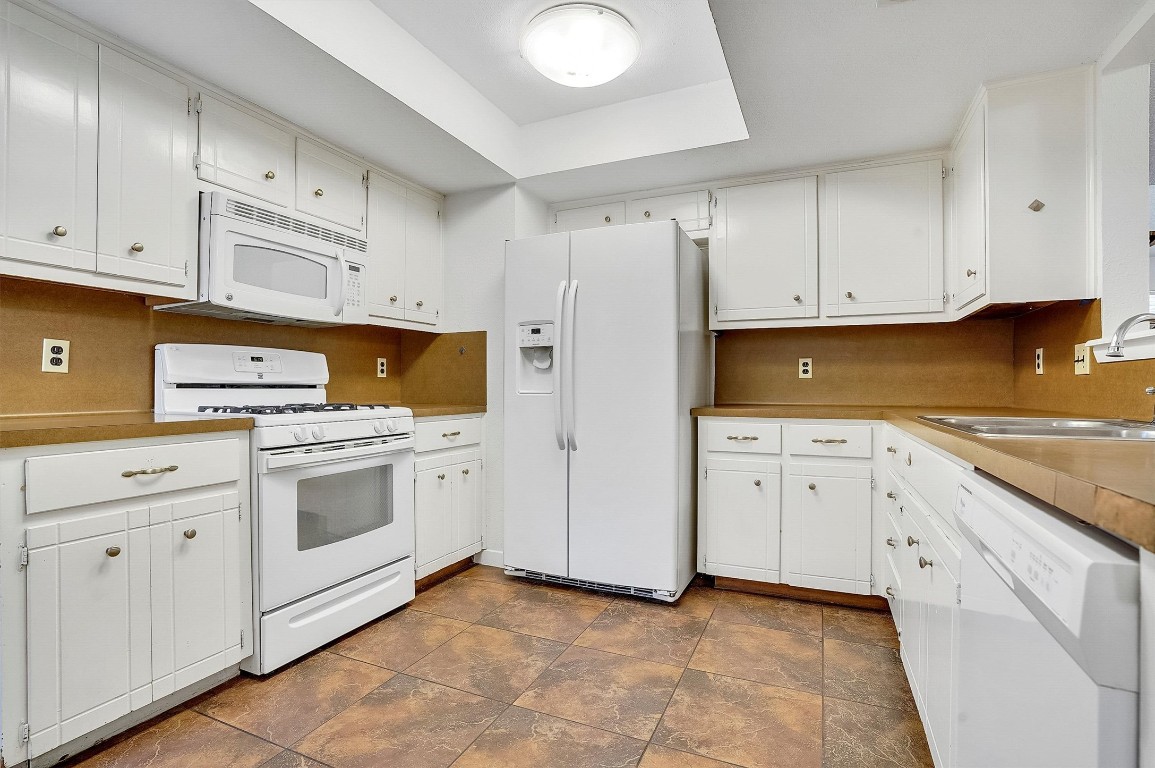 3201 Twinberry Cove, Unit B Austin, TX 78746 - Photo 7 of 19 a kitchen with granite countertop white cabinets and refrigerator