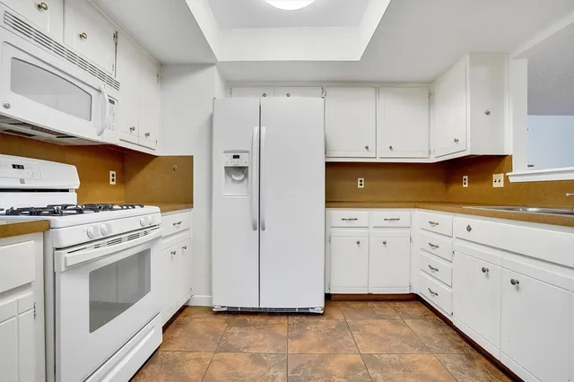 a kitchen with white cabinets and white appliances