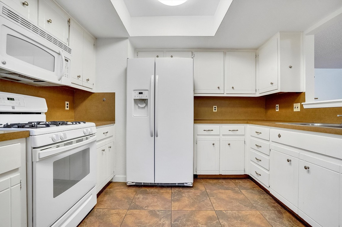 3201 Twinberry Cove, Unit B Austin, TX 78746 - Photo 8 of 19 a kitchen with white cabinets and white appliances