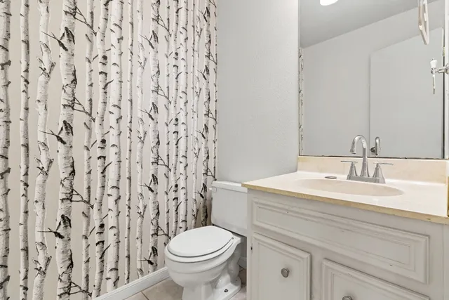 a bathroom with a granite countertop sink and a toilet