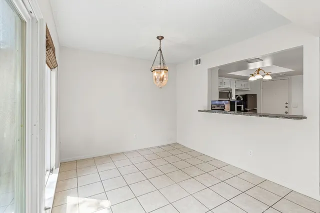 a view of an empty room with window and chandelier fan