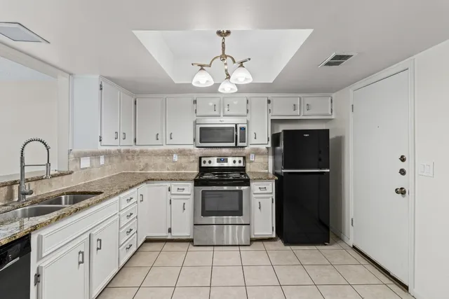 a kitchen with stainless steel appliances granite countertop a refrigerator a sink a stove and white cabinets