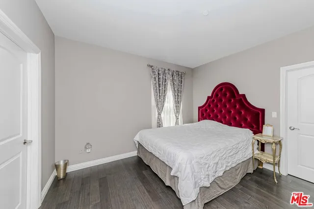 a bedroom with a bed a dresser and wooden floor