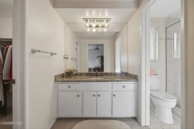 a spacious bathroom with a granite countertop sink a toilet and a mirror