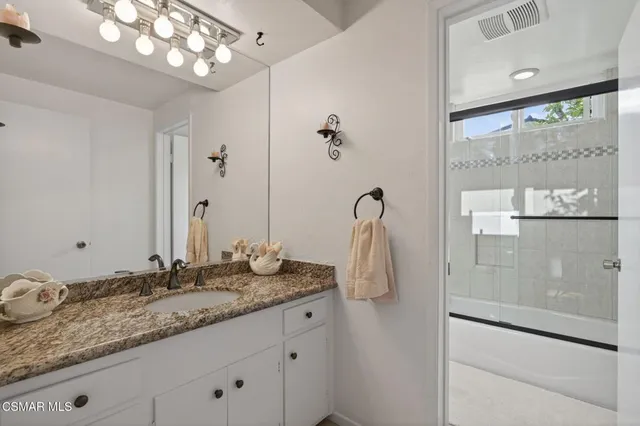 a bathroom with a granite countertop sink a mirror and a shower