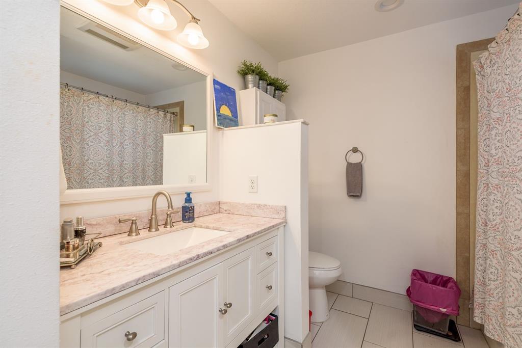 1333 McMullen Booth Road, Unit 1333 Clearwater, FL 33759 - Photo 13 of 26 a bathroom with a granite countertop sink a toilet and a mirror
