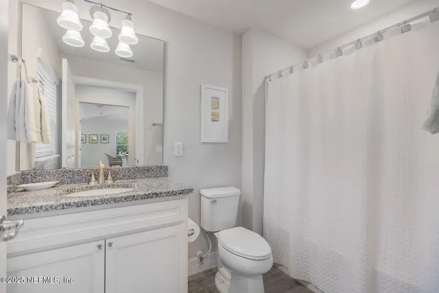 a bathroom with a granite countertop sink toilet and a mirror