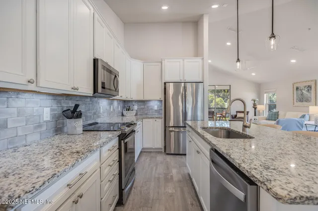 a kitchen with stainless steel appliances granite countertop a sink a stove and a refrigerator