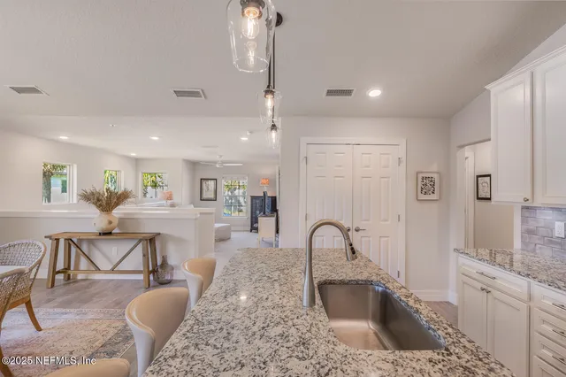 a kitchen with kitchen island granite countertop a sink a stove a dining table and chairs with wooden floor