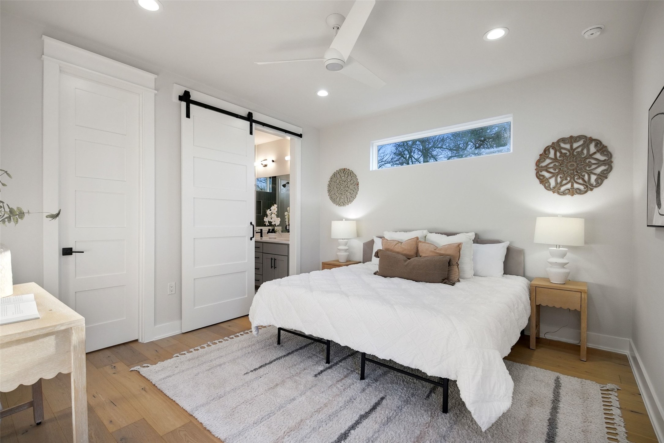 5109 Stone Gate Drive, Unit 2 Austin, TX 78721 - Photo 13 of 23 Bedroom with a barn door, light wood-style floors, ceiling fan, recessed lighting, and ensuite bathroom