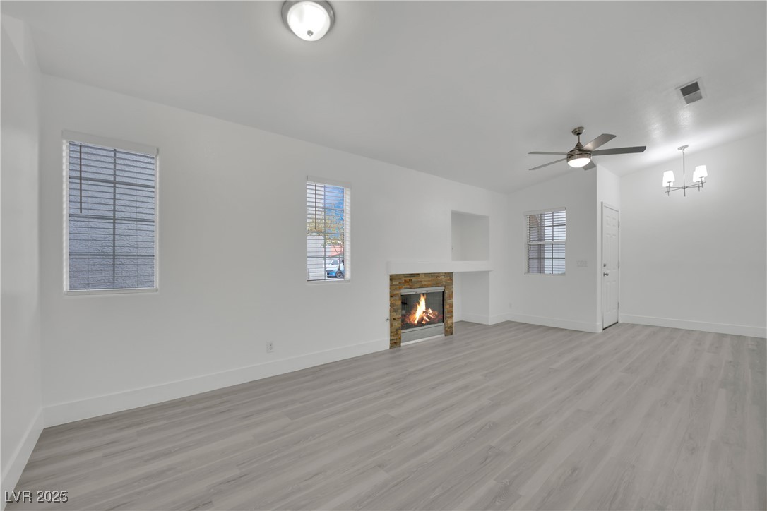 2218 Ramsgate Drive Henderson, NV 89074 - Photo 2 of 33 Unfurnished living room featuring light wood-type flooring, a fireplace, visible vents, and a healthy amount of sunlight