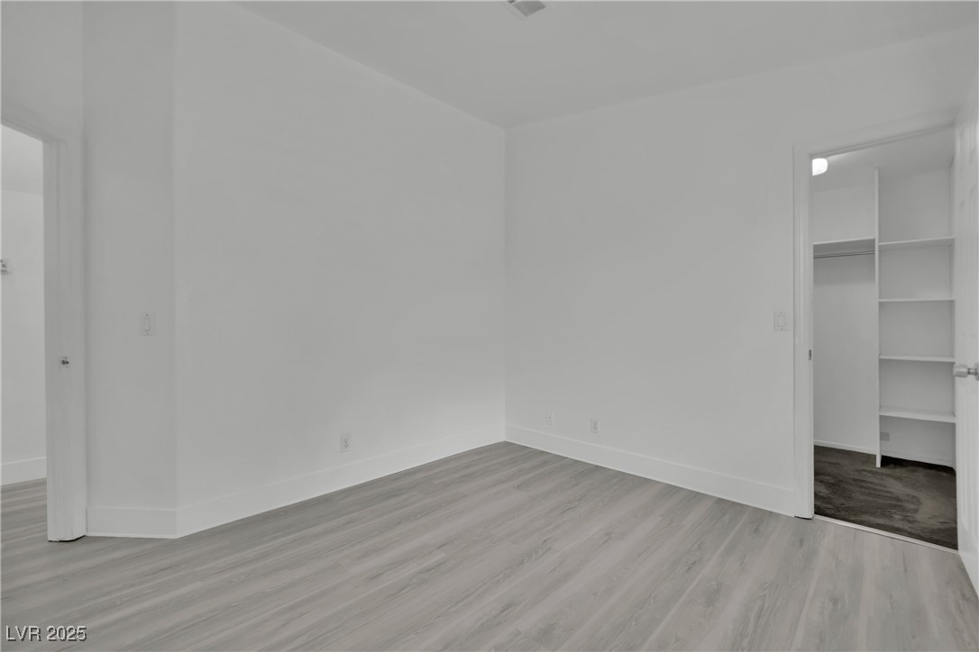 2218 Ramsgate Drive Henderson, NV 89074 - Photo 24 of 33 Unfurnished bedroom featuring light wood-style flooring, baseboards, a walk in closet, and a closet
