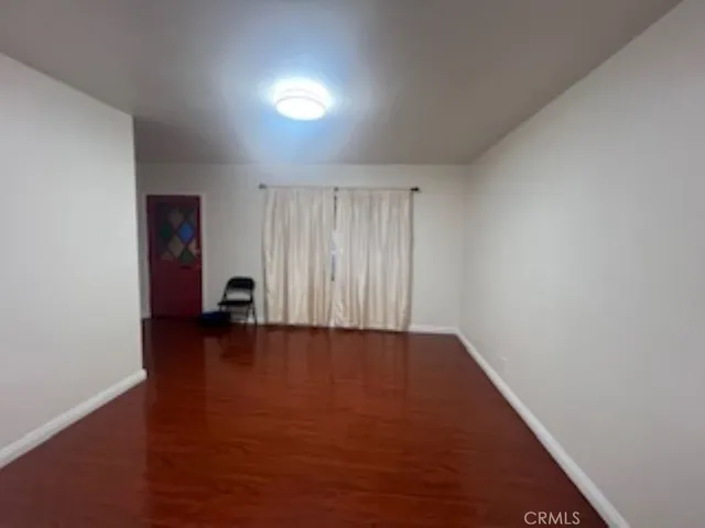 a view of an empty room with wooden floor and closet