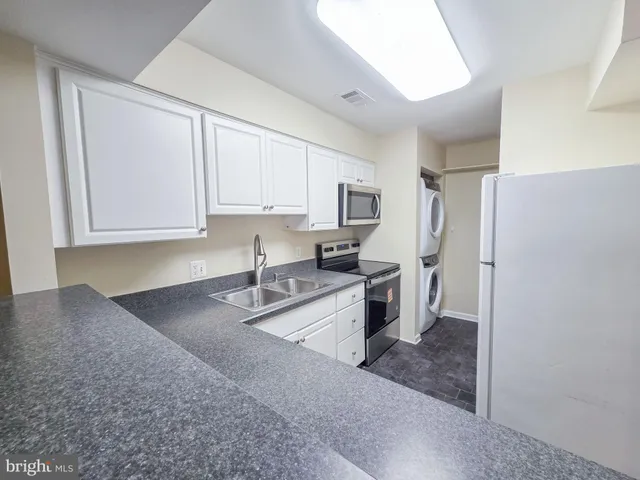 a kitchen with stainless steel appliances granite countertop a refrigerator sink and white cabinets