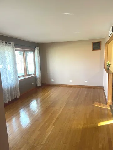 a living room with a table and a bookshelf with wooden floor