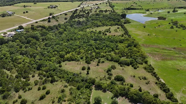 an aerial view of a residential houses with outdoor space and trees all around