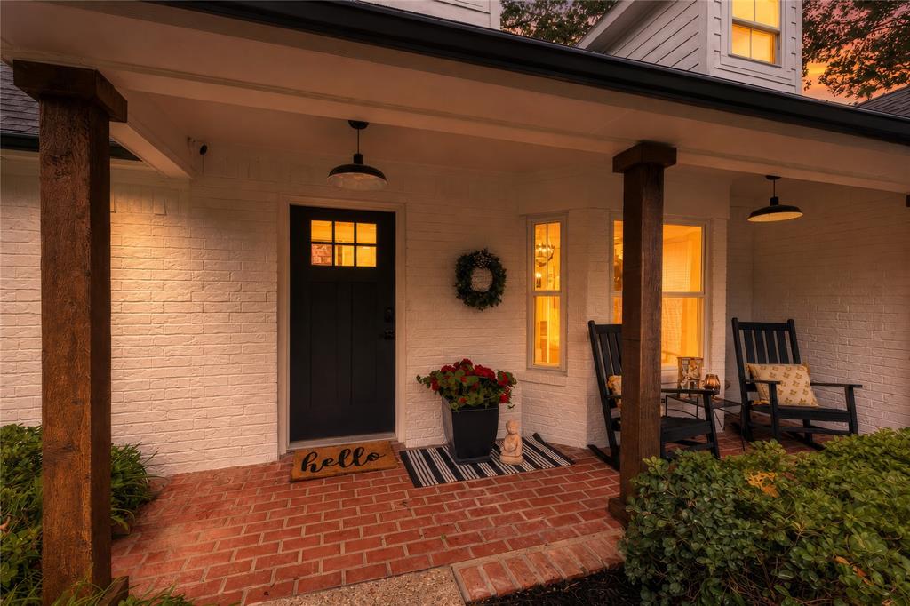 8948 David Fort Road Argyle, TX 76226 - Photo 2 of 39 Brick paver porch with dark wood-finish columns, white brick facade, and a dark paneled front door with upper glass lites