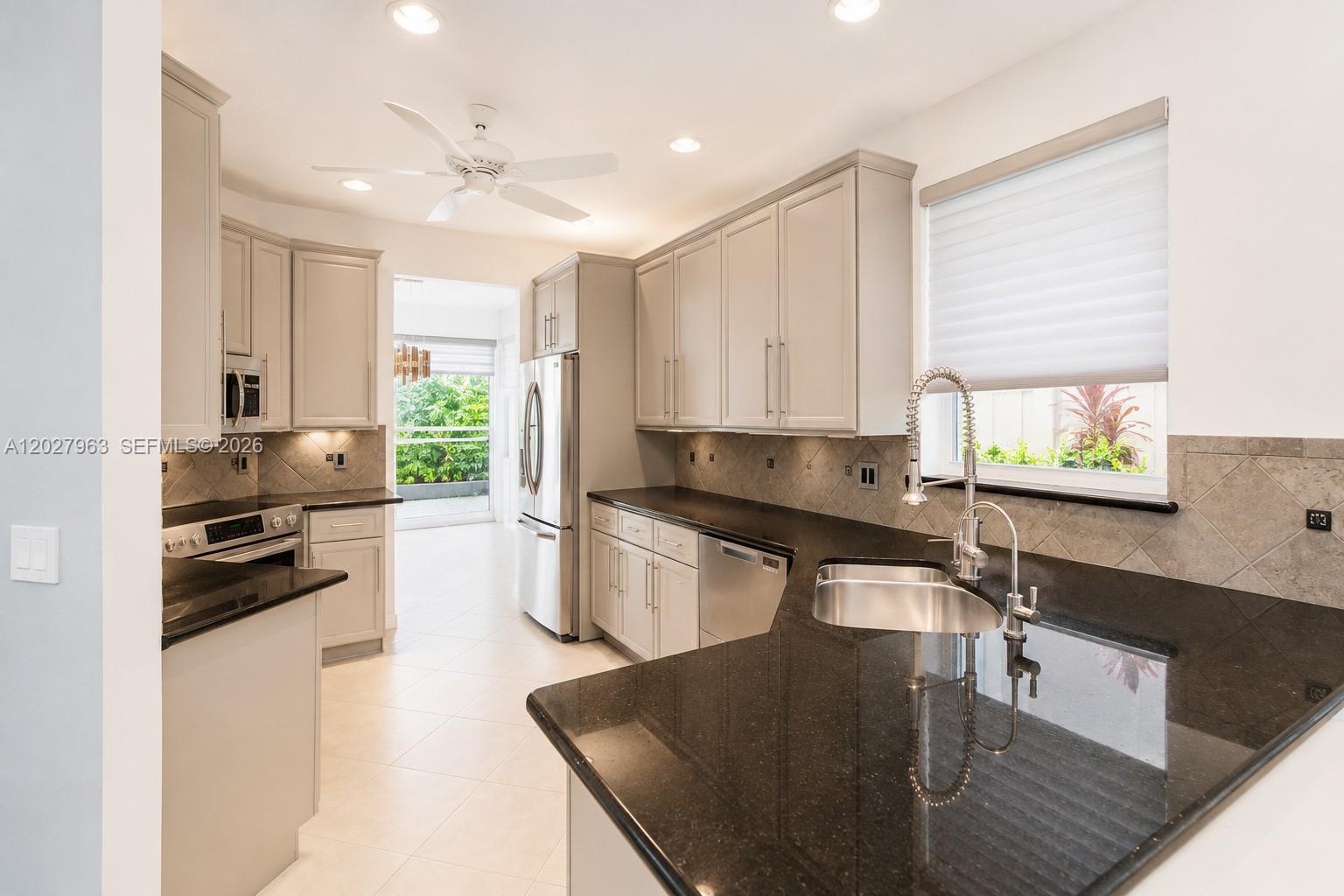 6646 Northwest 25th Terrace Boca Raton, FL 33496 - Photo 7 of 48 a kitchen with kitchen island granite countertop a stove a sink a refrigerator dining table and chairs