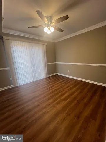 en empty room with wooden floor and fan