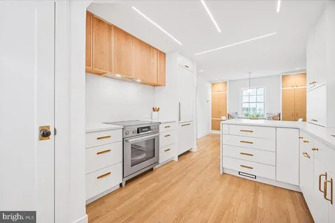 a kitchen with stainless steel appliances cabinets and a wooden floor