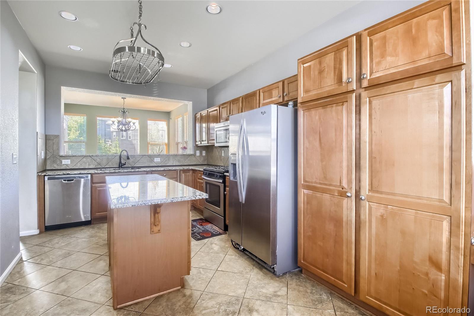 10861 Brooklawn Road Highlands Ranch, CO 80130 - Photo 6 of 30 a kitchen with stainless steel appliances granite countertop a refrigerator a sink and white cabinets