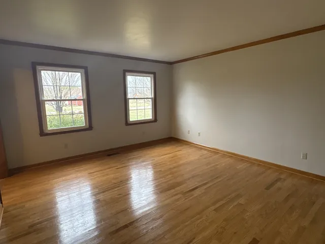 a view of an empty room with wooden floor and windows