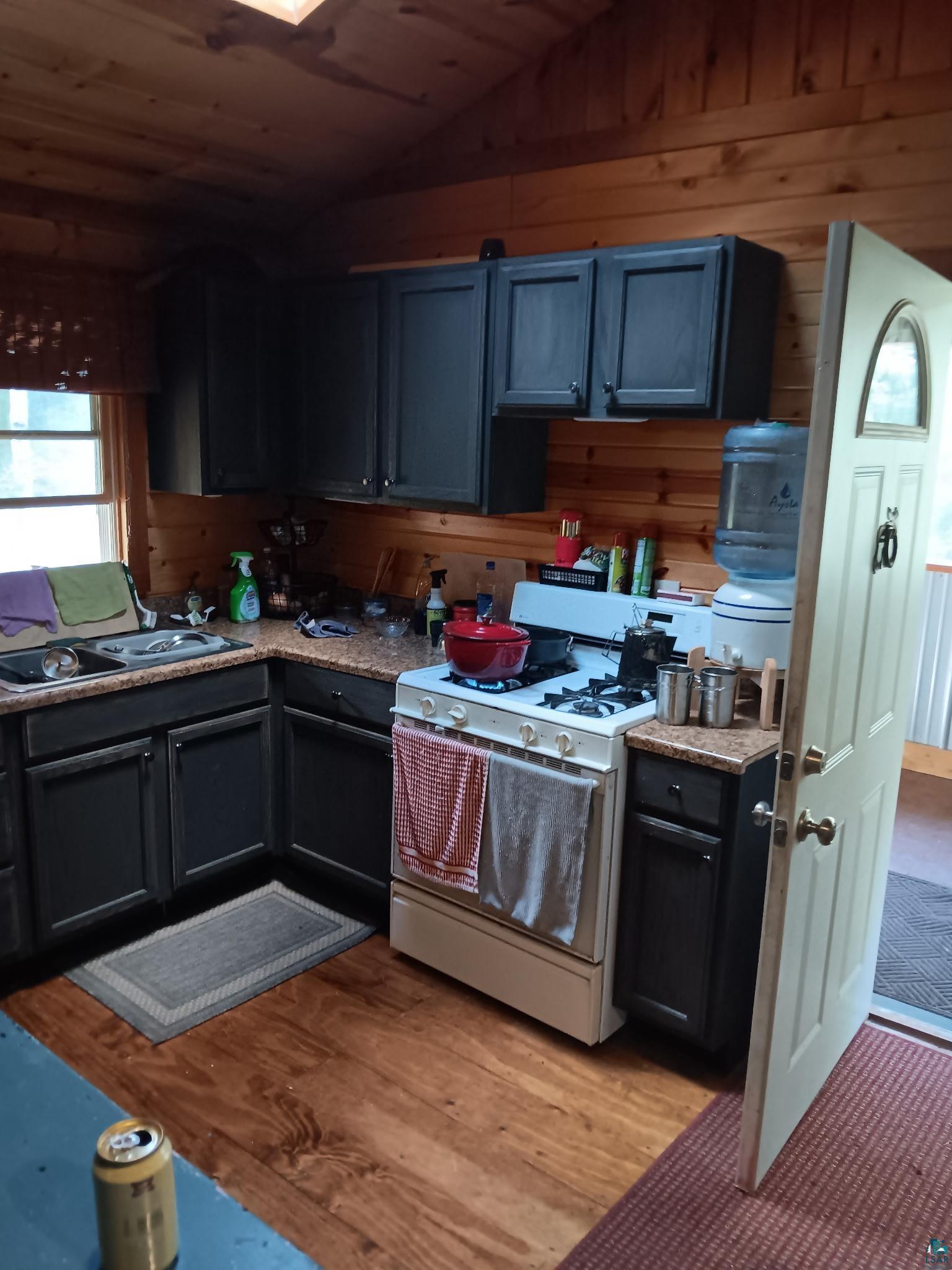 4002 Shilo Trail Ely, MN 55731 - Photo 5 of 15 Kitchen featuring white gas range, wood walls, vaulted ceiling, wood ceiling, and dark wood finished floors