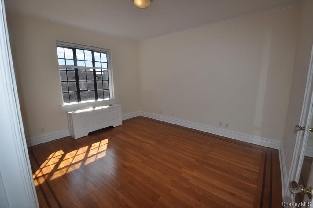 155 Garth Road, Unit 5H Scarsdale, NY 10583 - Photo 21 of 30 an empty room with wooden floor and windows