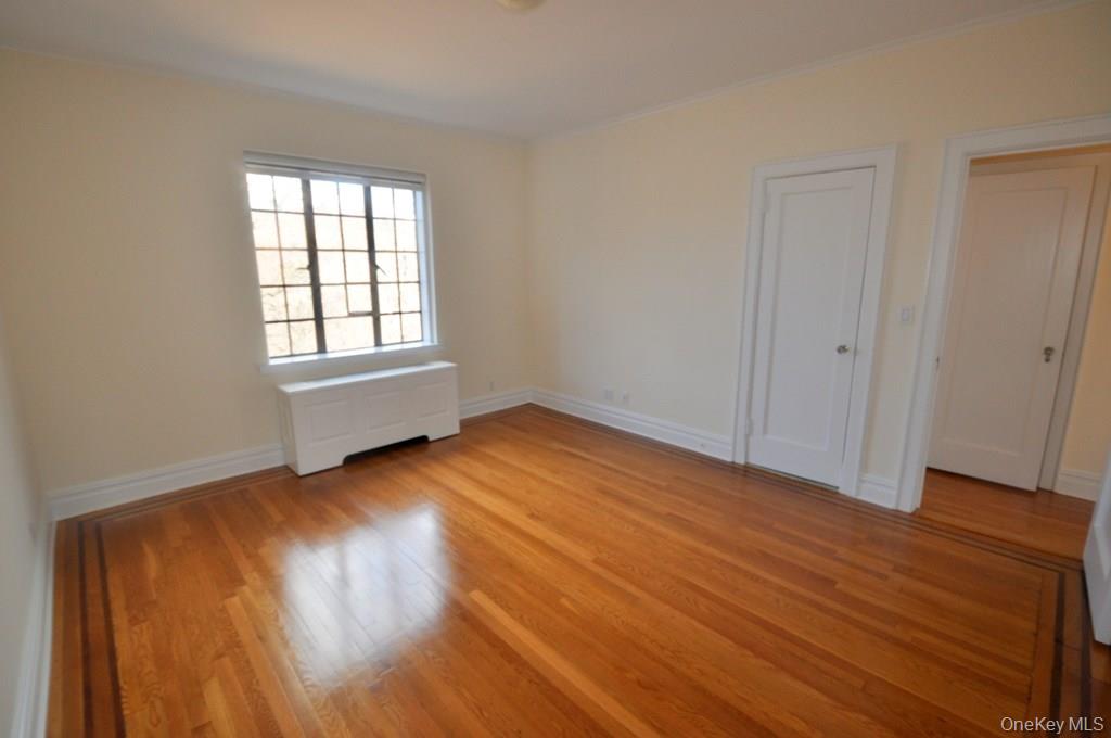 155 Garth Road, Unit 5H Scarsdale, NY 10583 - Photo 25 of 30 an empty room with wooden floor and windows