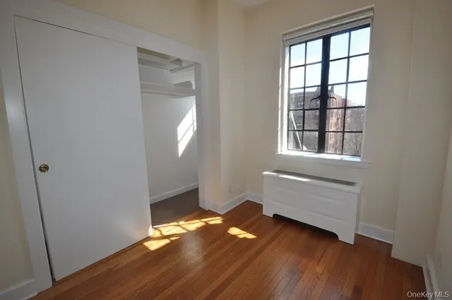an empty room with wooden floor cabinet and windows