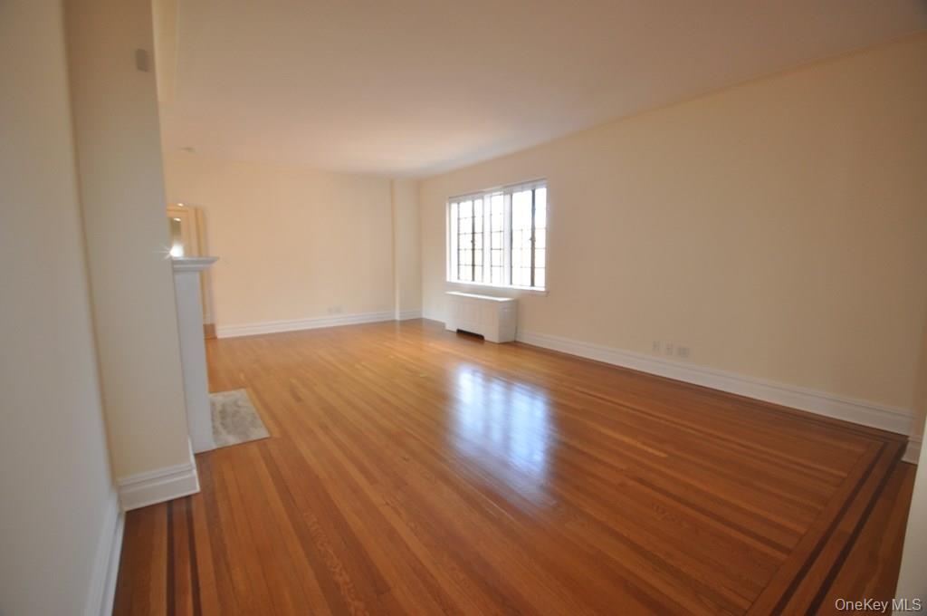 155 Garth Road, Unit 5H Scarsdale, NY 10583 - Photo 6 of 30 an empty room with wooden floor and windows