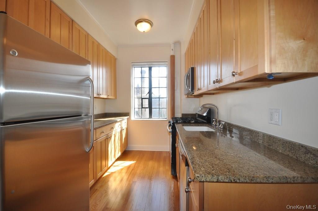 155 Garth Road, Unit 5H Scarsdale, NY 10583 - Photo 7 of 30 a kitchen with stainless steel appliances granite countertop a sink a stove and a refrigerator