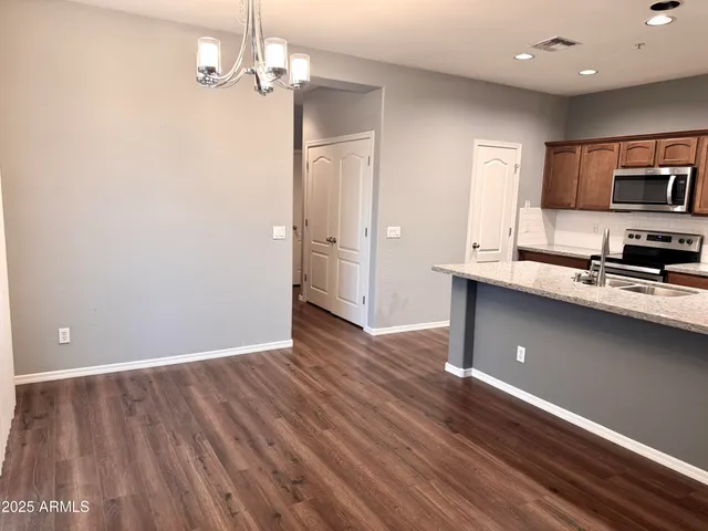 a view of a kitchen with stainless steel appliances granite countertop a refrigerator a sink dishwasher a stove and white countertops with wooden floor