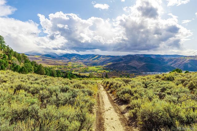 a view of a house with a yard and large trees