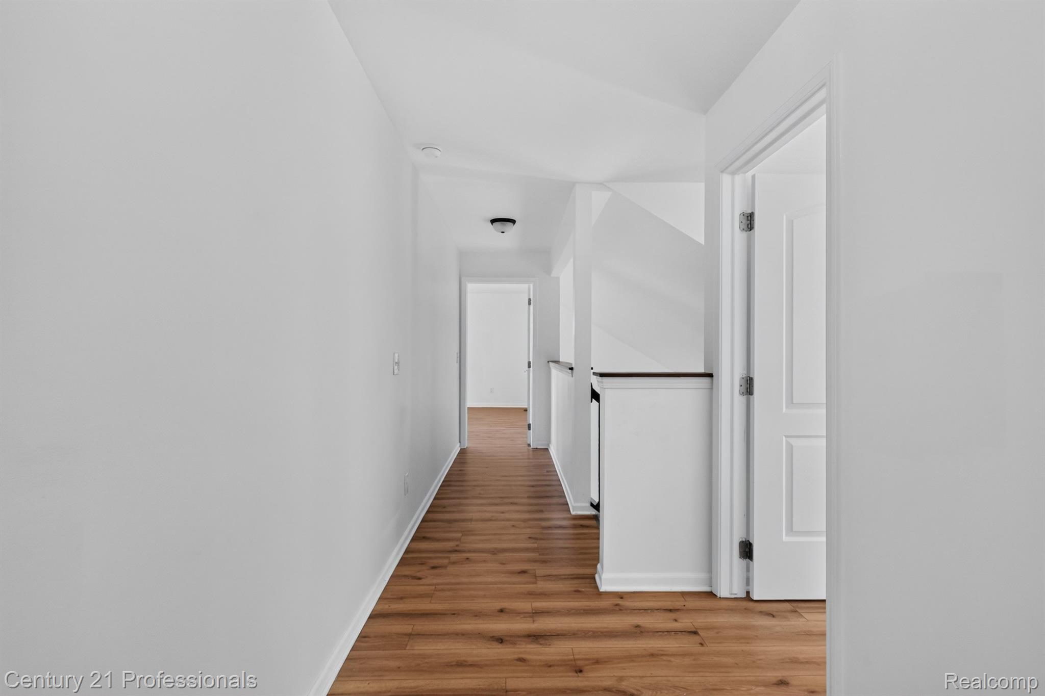 2042 Decker Road Walled Lake, MI 48390 - Photo 27 of 48 Bright hallway leading to 3 other bedrooms on opposite side of home featuring wood-finish flooring, white walls, and white trim