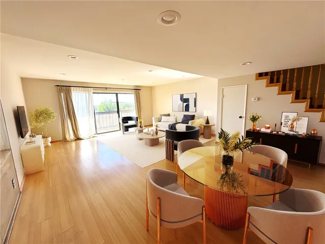 a living room with dining room and couches with wooden floor