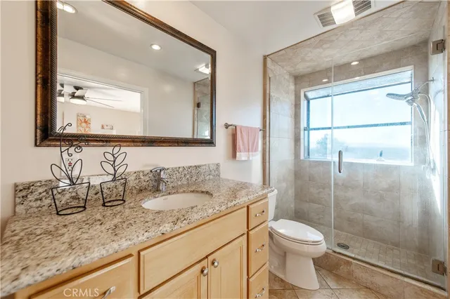 a bathroom with a granite countertop sink a toilet and a mirror