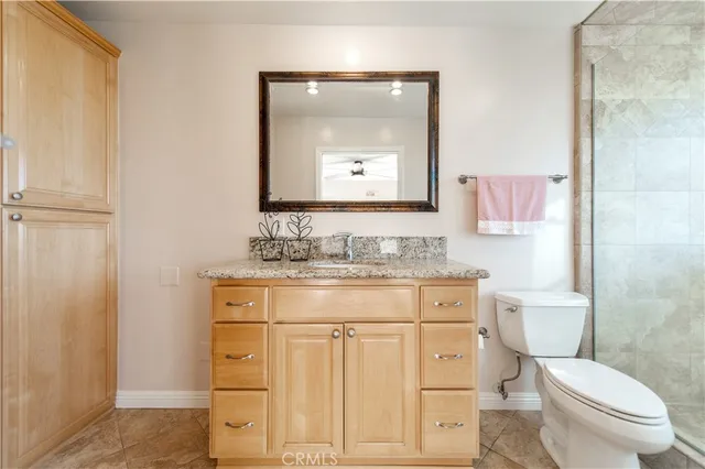 a bathroom with a granite countertop toilet sink and mirror