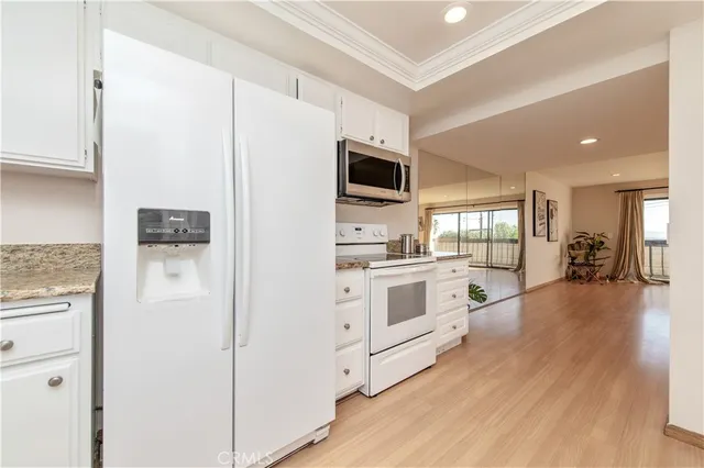 a white kitchen with stainless steel appliances a refrigerator and a stove top oven